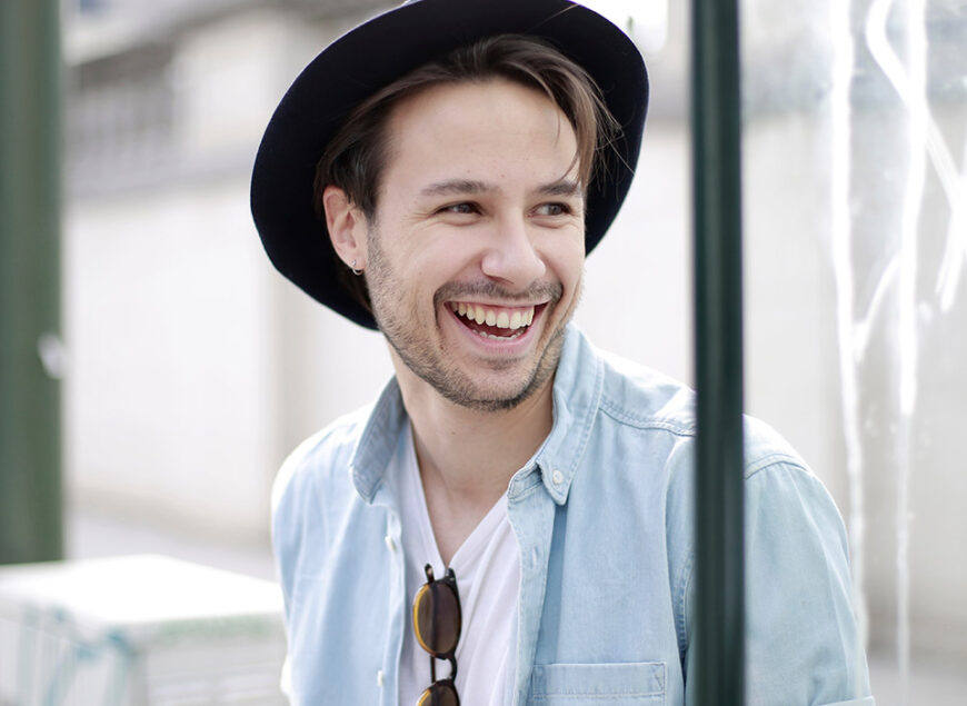 Smiling young man in hat outdoors