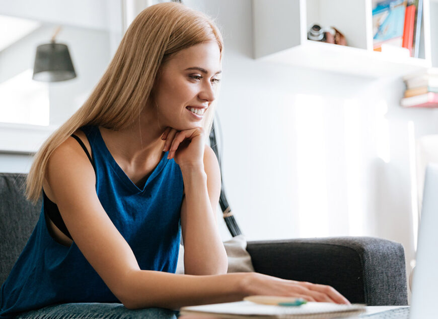 Smiling young woman using laptop on sofa