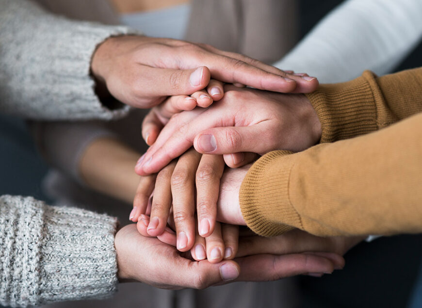 Close-up of stacked hands showing teamwork and support