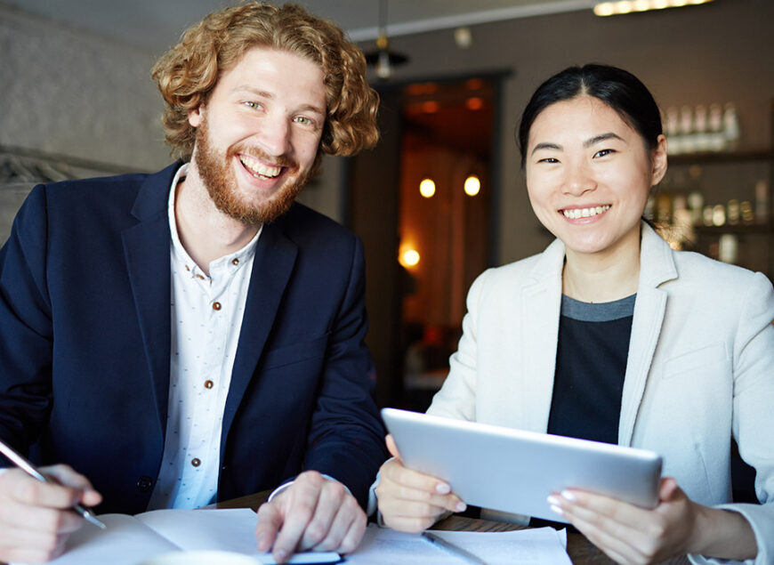 Two smiling coworkers with tablet and documents