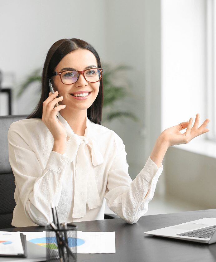 Smiling woman talking on phone at desk.
